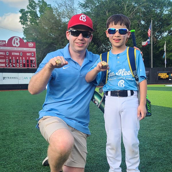 Dr. J. Chase Findley and his son pose with their Bellaire Little League championship rings on one of the league's fields