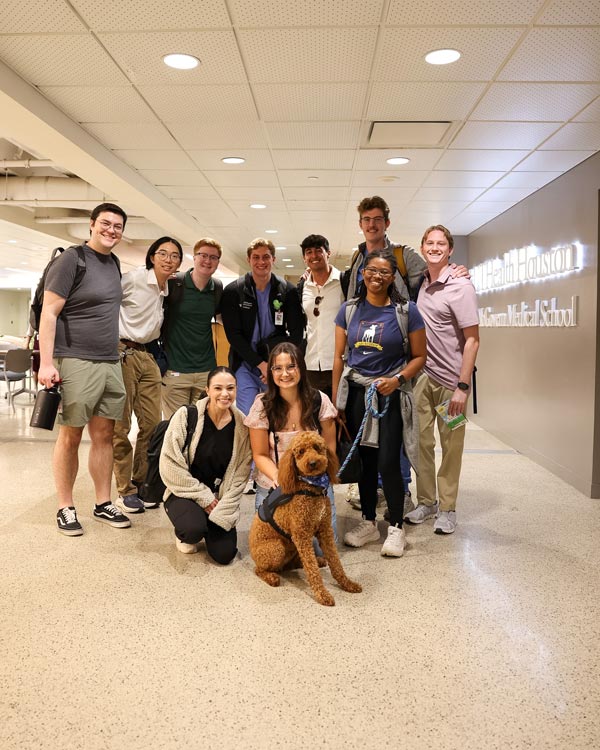 A group of medical students gathers with a therapy dog in the McGovern Medical School student commons on the first day of the academic year.