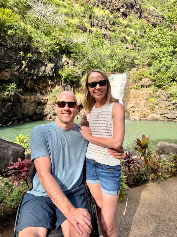 Kristina Tebo, MD, poses with her husband in front of a waterfall and lush tropical vegetation during a trip to Hawaii.