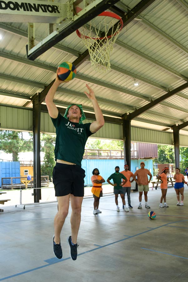McGovern Medical School student jumps toward a basketball hoop for a layup during the Henry W. Strobel Retreat.