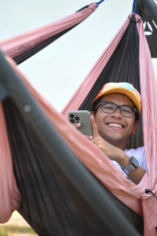 McGovern Medical School student smiles while relaxing in a hammock and looking at a cellphone during the Henry W. Strobel Retreat.