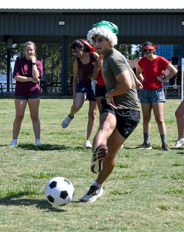 McGovern Medical School student kicks a soccer ball as classmates watch during an outdoor activity at the Henry W. Strobel Retreat.
