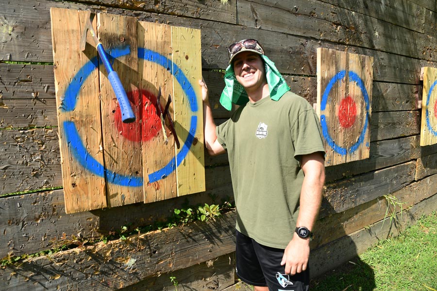 McGovern Medical School student smiles beside an axe-throwing target after landing an axe near the bull's-eye.