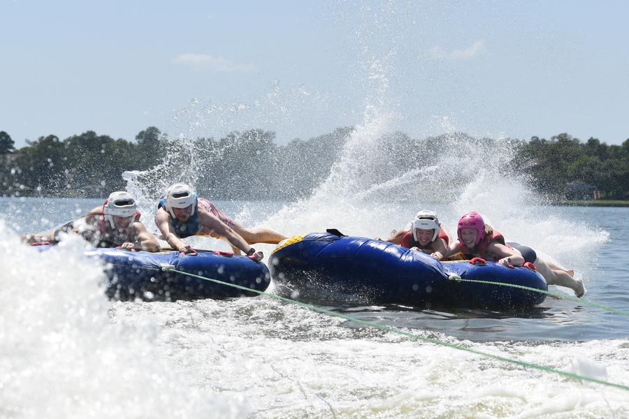 McGovern Medical School students hold onto inflatable tubes as they bounce across the wake while tubing on the lake.
