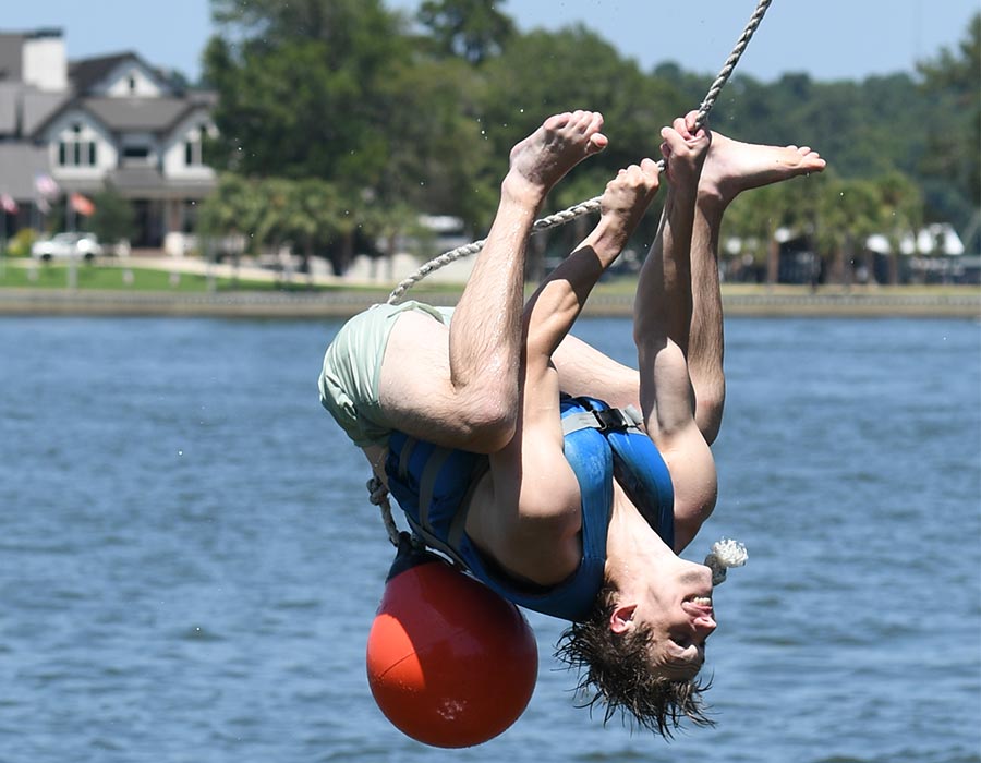 McGovern Medical School student hangs upside down from a rope over the lake during an outdoor activity at the Henry W. Strobel Retreat.