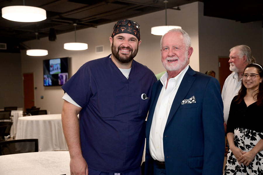 Richard Andrassy, MD, poses with a colleague in surgical scrubs during a celebration honoring his retirement as chair.