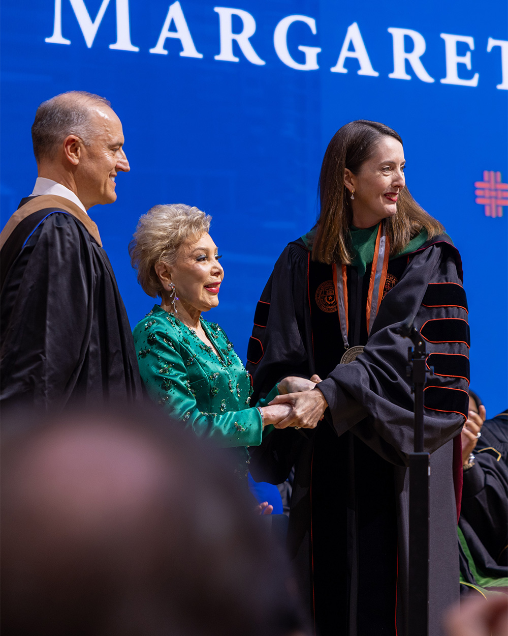 Melina R. Kibbe, MD, shakes hands with Margaret Alkek Williams during her presidential investiture ceremony as UTHealth Houston leaders look on.