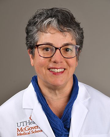 Dr. Pamela Promecene poses for a professional headshot in a traditional white coat with blue shirt